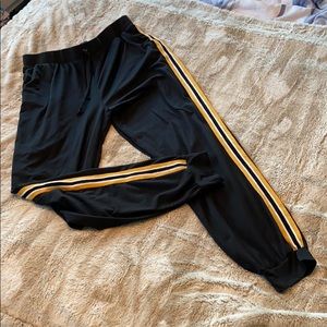 Black joggers with white and gold stripe detail.